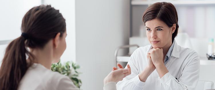 Photo of a woman speaking to a listening doctor